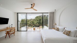 A modern bedroom with a large bed, a desk, and a balcony with chairs. - Elements A3 Villa Bingin (Pecatu)