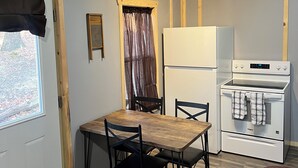 Una cocina compacta con una mesa y sillas de madera, un refrigerador y un horno.