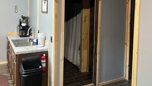 Una habitación con cocina, una escalera y una puerta que da a otra estancia.