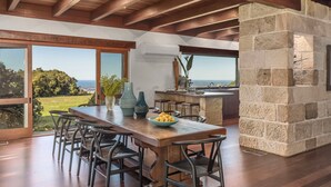 A spacious kitchen with a stone wall, large windows, and a view of the ocean.