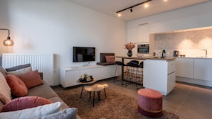 A modern living room with a sofa, a coffee table, and a TV. There is a kitchen area with a dining table and chairs. - Baelskaai 25 with balcony by Interhome (Oostende)