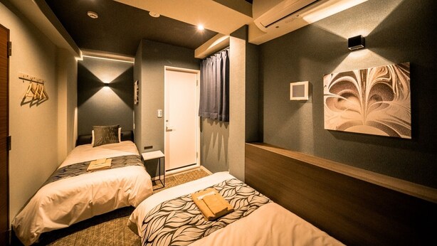 Ein Hotelzimmer mit zwei Betten, einem Schreibtisch und einer Dusche.