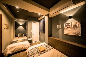 Ein Hotelzimmer mit zwei Betten, einem Schreibtisch und einer Dusche.