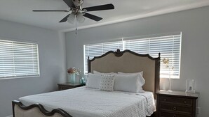 Ein Schlafzimmer mit Bett, Nachttisch, Kommode und Deckenventilator.