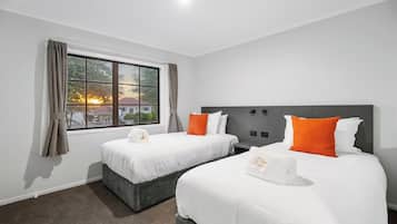 A hotel room with two beds, a large window, and a view of the sunset.