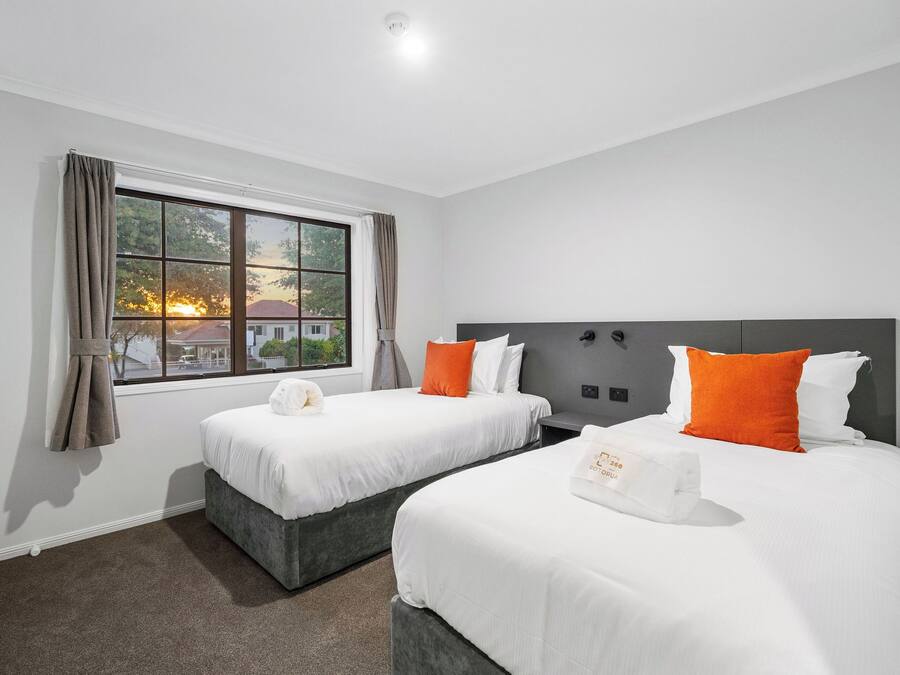A hotel room with two beds, a large window, and a view of the sunset.