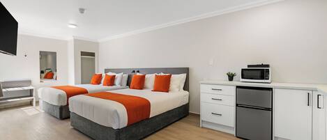 Una habitación de hotel moderna con una cama grande, un escritorio, un microondas y un refrigerador.
