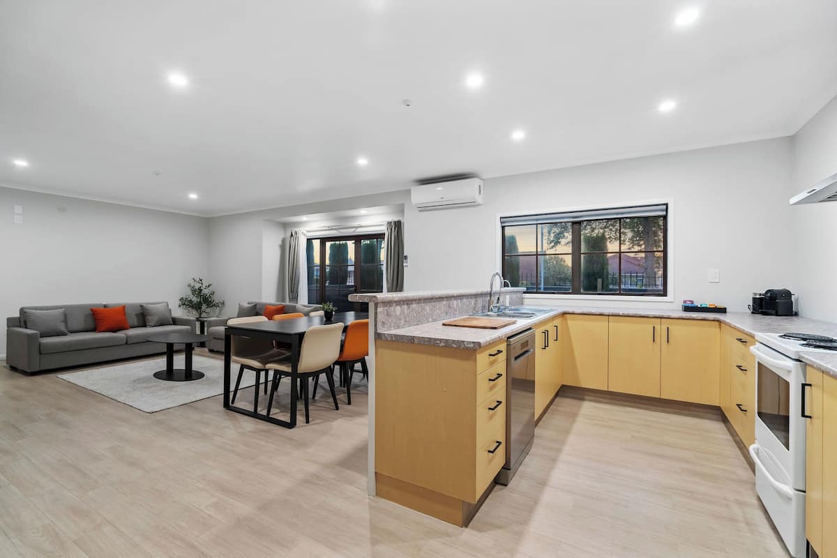 A modern kitchen with wooden cabinets, a built-in oven, and a large window.