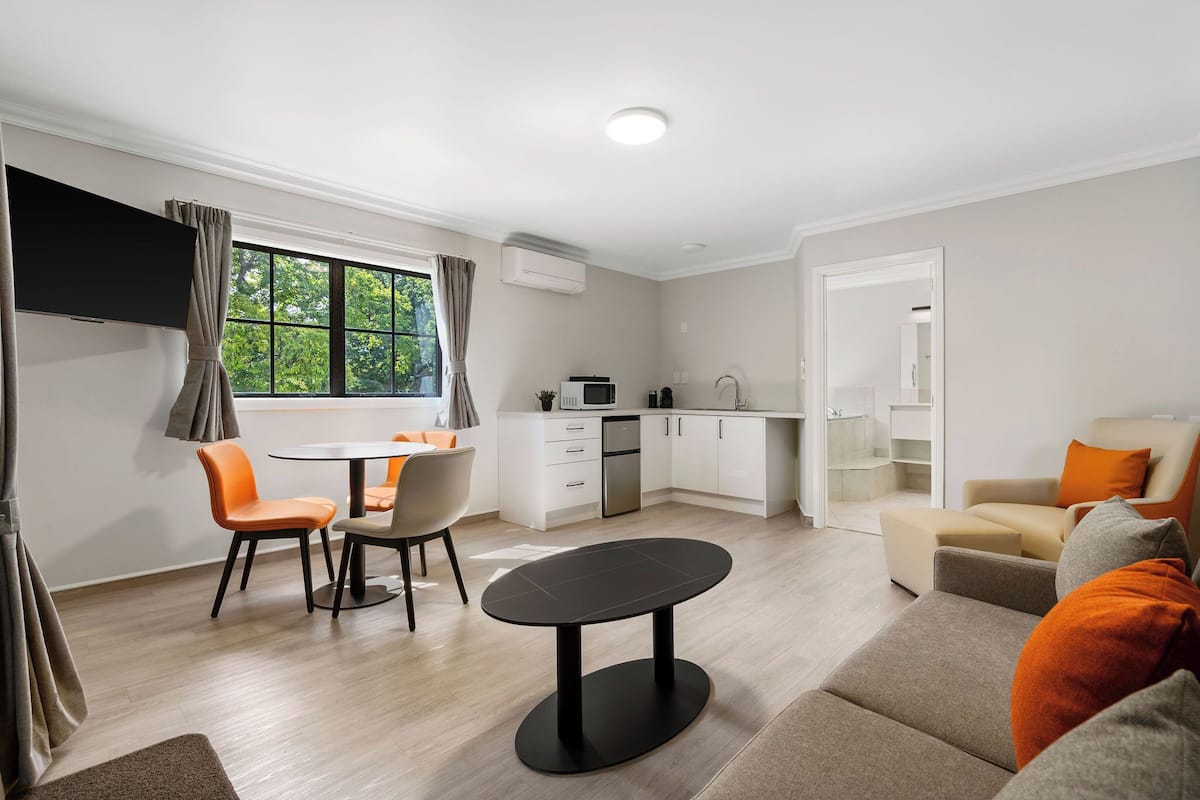 A modern living room with a dining area, a kitchen, and a seating area with a sofa and armchairs.