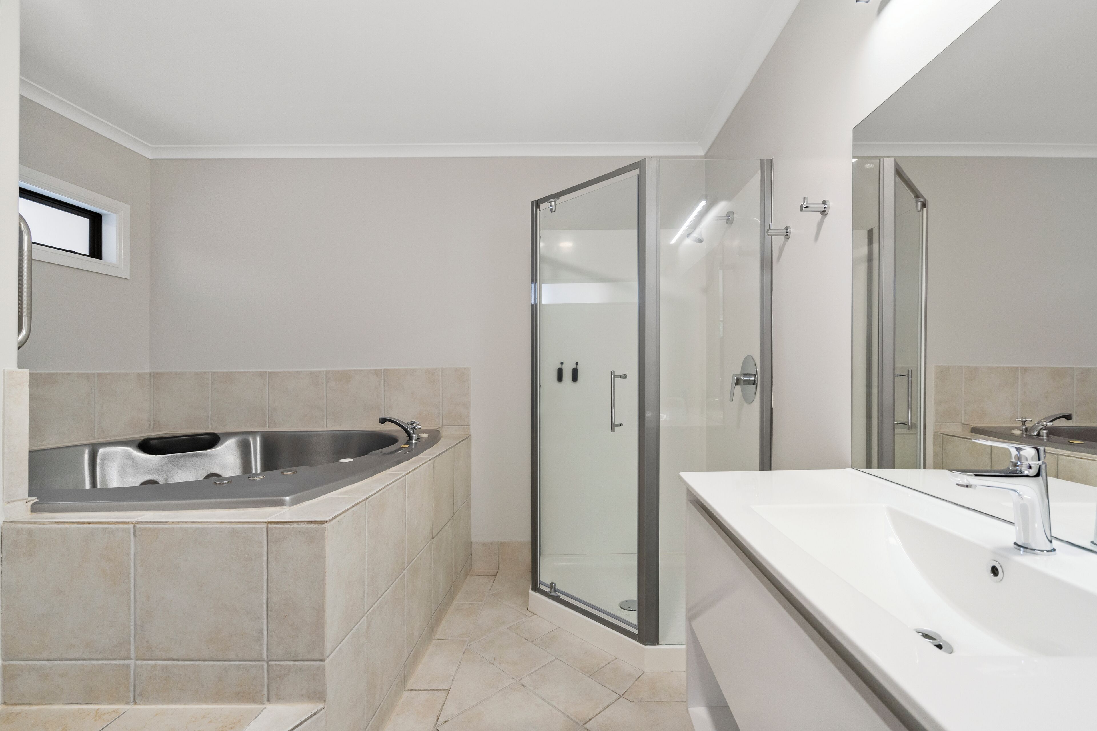 Ein modernes Badezimmer mit einer freistehenden Badewanne, einer gläsernen Duschkabine und einem großzügigen Waschtisch mit Spüle.