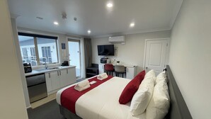 A hotel room with a bed, a desk, a TV, and a kitchenette. - STAY280 & STAY284 Rotorua (Rotorua)