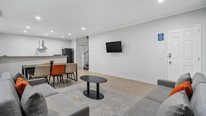 A modern living room with a grey sofa, a round coffee table, and a dining area with a table and chairs. - STAY280 & STAY284 Rotorua (Rotorua)