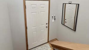 A hallway with a wooden door, a small window, and a mirror on the wall.