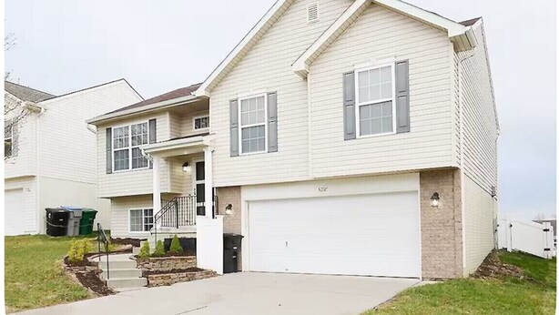 A two-story residential house with a front garage, a covered porch, and a small front yard with landscaping.