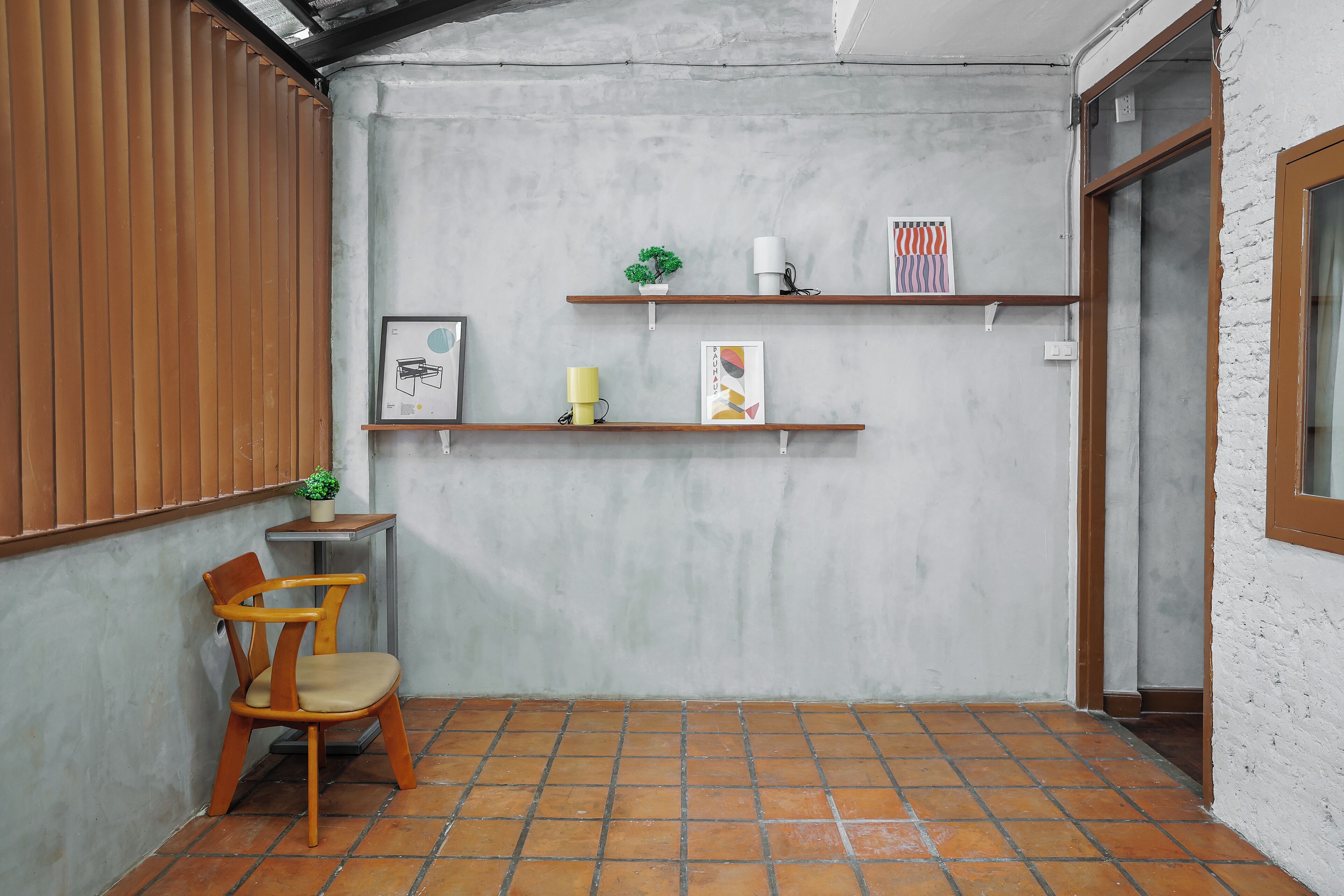 A corner room with a wooden chair, a small table, and two shelves with decorative items.