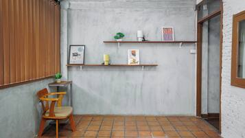 A corner room with a wooden chair, a small table, and two shelves with decorative items.