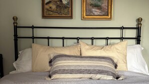 A bed with a quilted cover, a metal headboard, and two framed paintings on the wall. - Lake House Retreat with a Dock & Boat (Västra Götalands län)