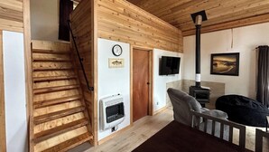A wooden interior with a staircase, a fireplace, a television, and a painting on the wall. - Ocean front 2-bedroom cabin in Whale Pass with strong WiFi (Whale Pass)
