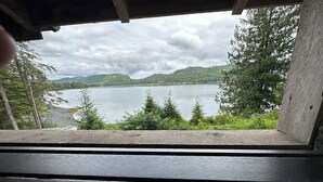 A view from a window overlooking a lake with trees and hills in the background.