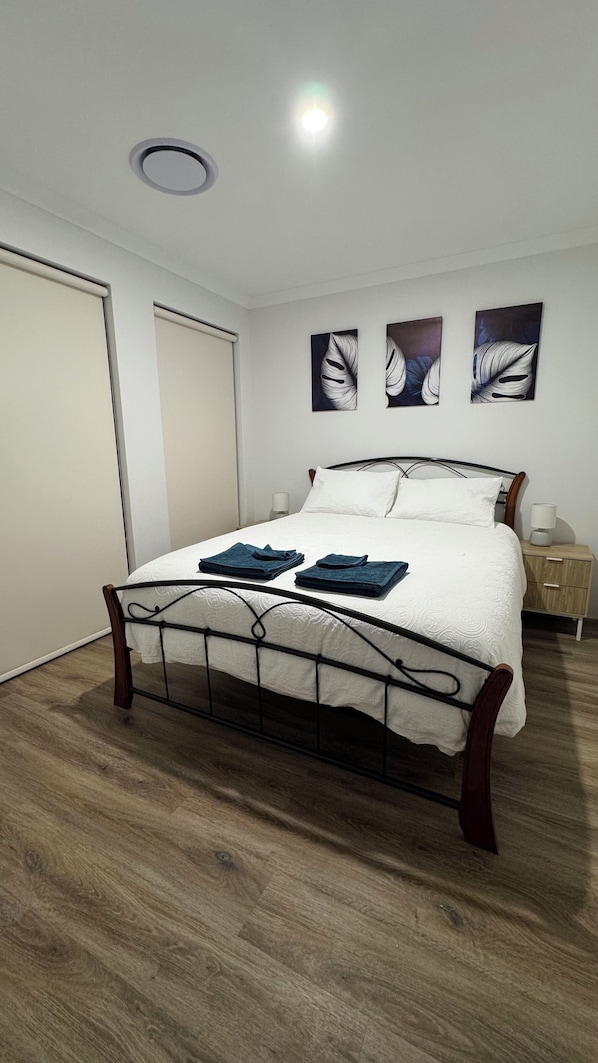 Restful retreat with a central bed, white linens, and a nightstand with a lamp.