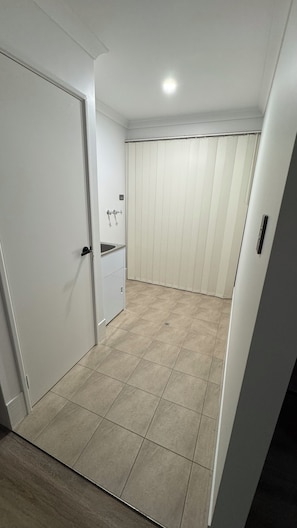 Enter a serene space with a door to the left and a window to the right, leading to a room with a sink.