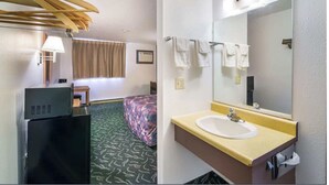 A hotel room with a bed, a desk with a lamp, a dresser, a bathroom with a sink and mirror, and a window with curtains.