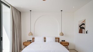 Une chambre à coucher avec un grand lit, deux tables de chevet, une œuvre d’art accrochée au mur et une fenêtre avec des rideaux.