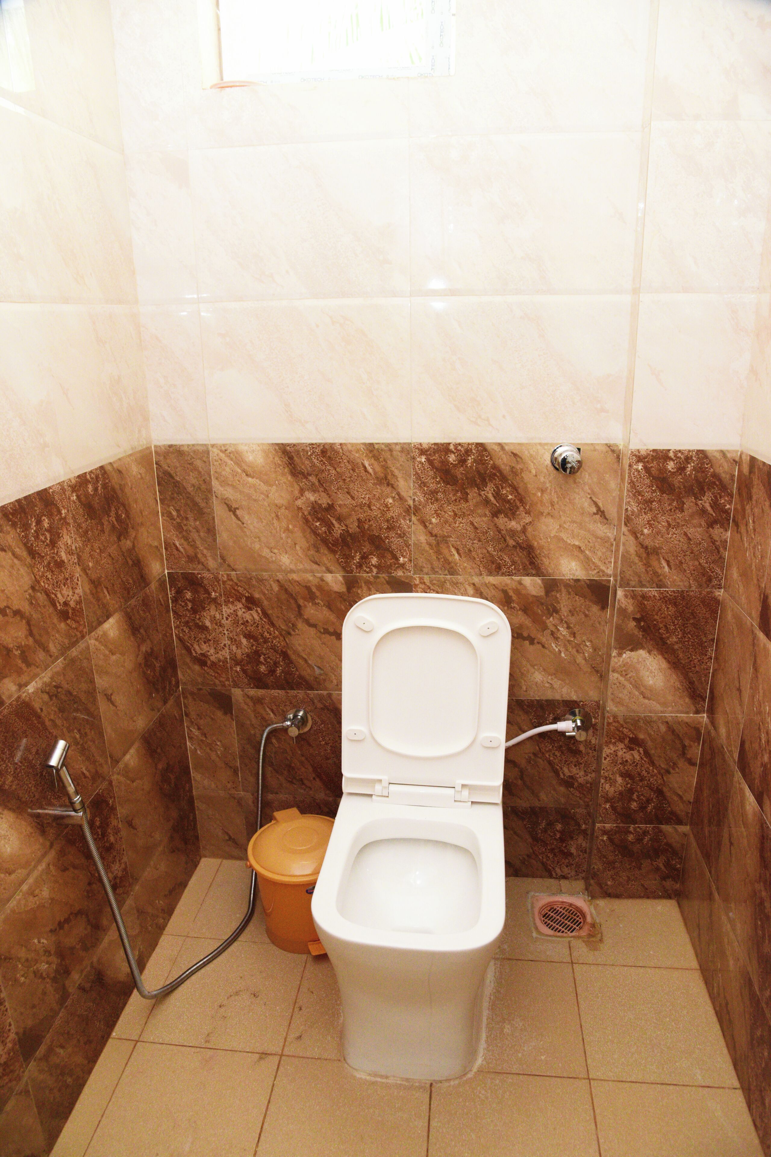 Un baño con inodoro, ducha y un cubo de basura.