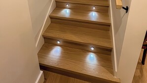 A wooden staircase with built-in lighting and a handrail. - Tastefully furnished new studio in Bear Mountain (Langford)