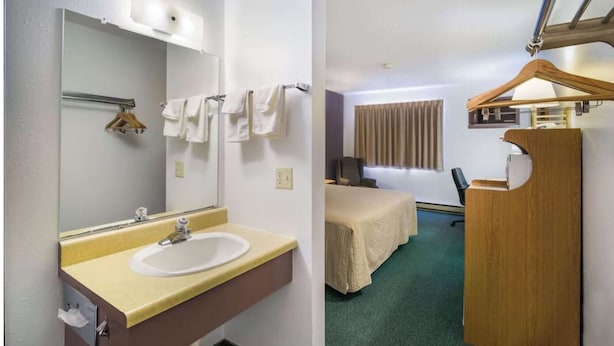 Habitación de hotel con baño que incluye un lavamanos, espejo y toallero. La habitación también tiene una cama, un escritorio y una silla.