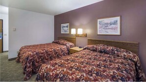 Una habitación de hotel con dos camas, una mesita de noche y dos lámparas fijadas a la pared.