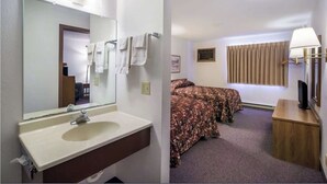 Habitación de hotel con baño que incluye un lavamanos y un espejo, dos camas con ropa de cama estampada, una ventana con cortinas y una mesita de noche con lámpara.