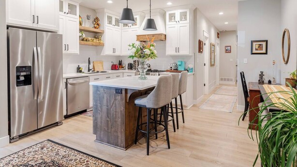 A modern kitchen with white cabinets, stainless steel appliances, and a central island with bar stools.