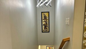 A staircase with a modern light fixture, a framed artwork above, and a plant on the left.