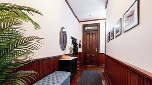 Un couloir avec un banc en bois, un miroir, une porte et des tableaux encadrés accrochés au mur.