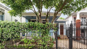 Un quartier résidentiel doté d’une entrée sécurisée, d’un chemin bordé d’arbres et d’une maison avec un porche.