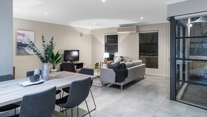 A modern living room with a sofa, TV, and dining area.