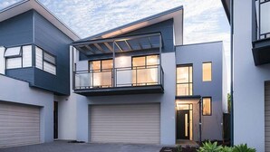 A modern two-story house with a garage, a covered balcony, and a well-maintained garden.