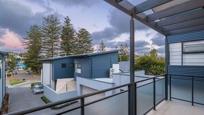 A modern residential building with a balcony, a garage, and a driveway.