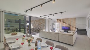 A modern interior with a dining area, a living room, and a stone wall.