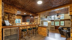 Una cocina rústica con pared de piedra, techo de madera y una barra con taburetes.