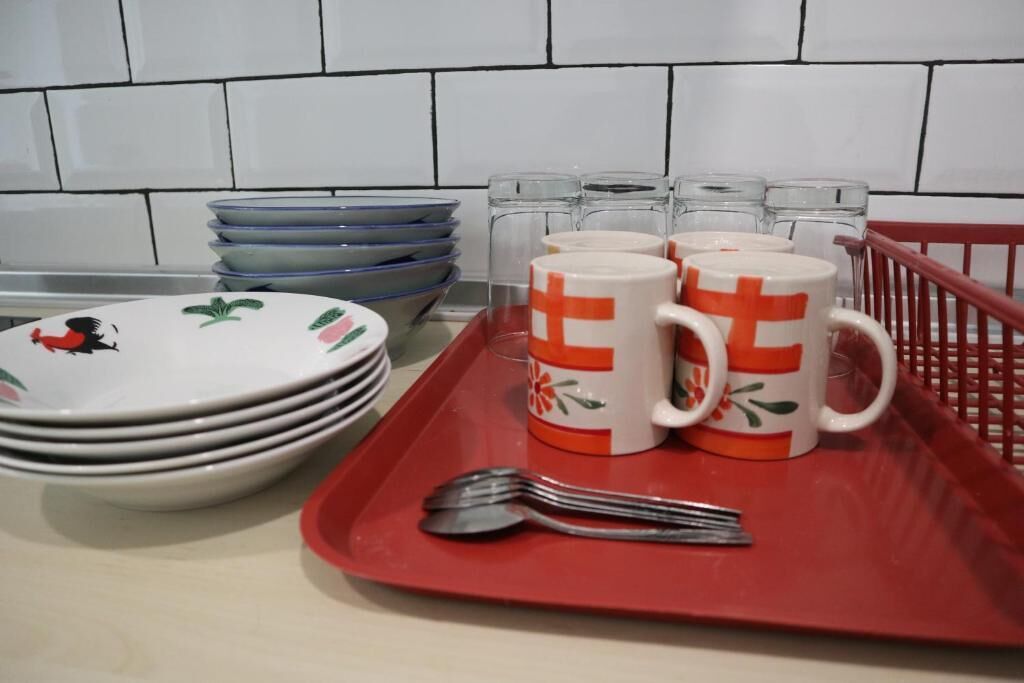 Una encimera de cocina con platos apilados, una bandeja roja con dos tazas y una cuchara.