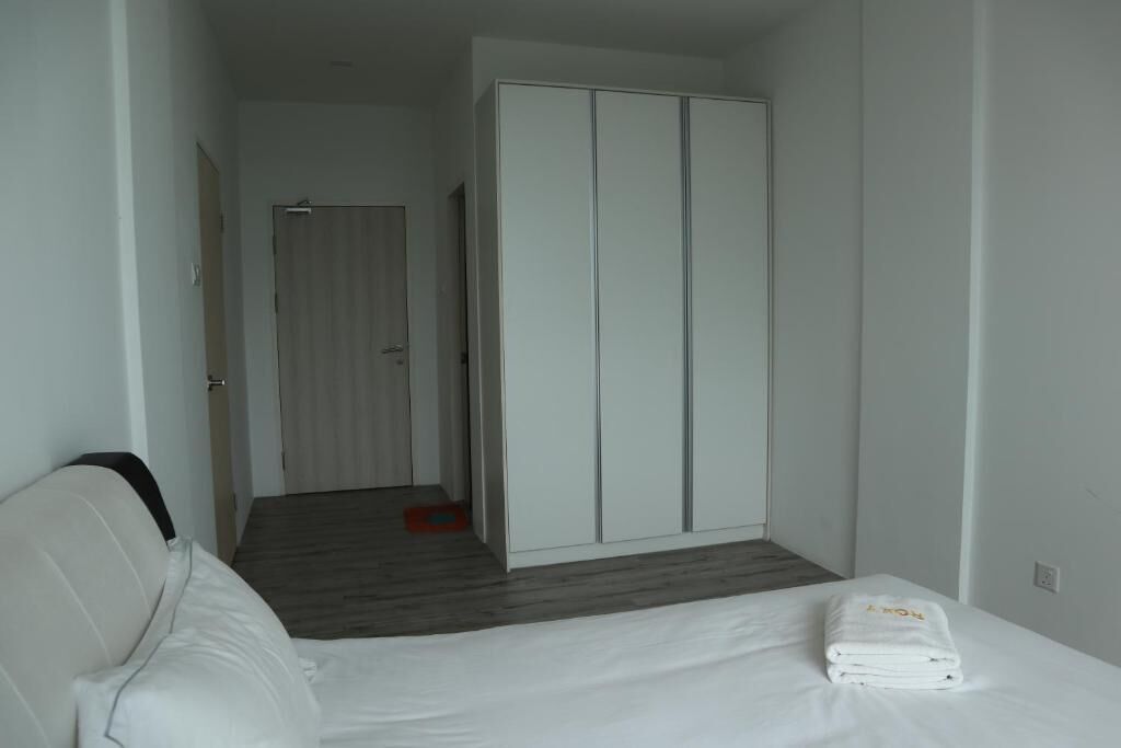 A hotel room with a bed, a white wardrobe, and a wooden floor.