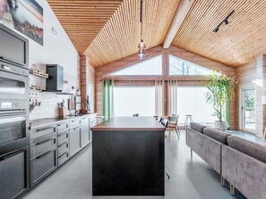 Una cocina moderna con una isla central, electrodomésticos integrados y techo de madera.