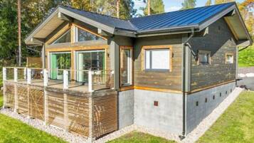 Une maison moderne avec un toit en pente, de grandes fenêtres et une terrasse.
