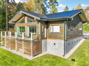A modern house with a sloped roof, large windows, and a deck.