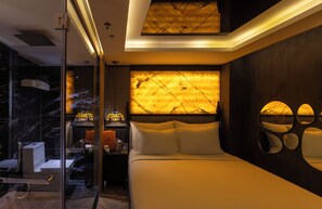 Camera da letto moderna con un letto grande, un pannello divisorio in vetro e un design di parete originale.