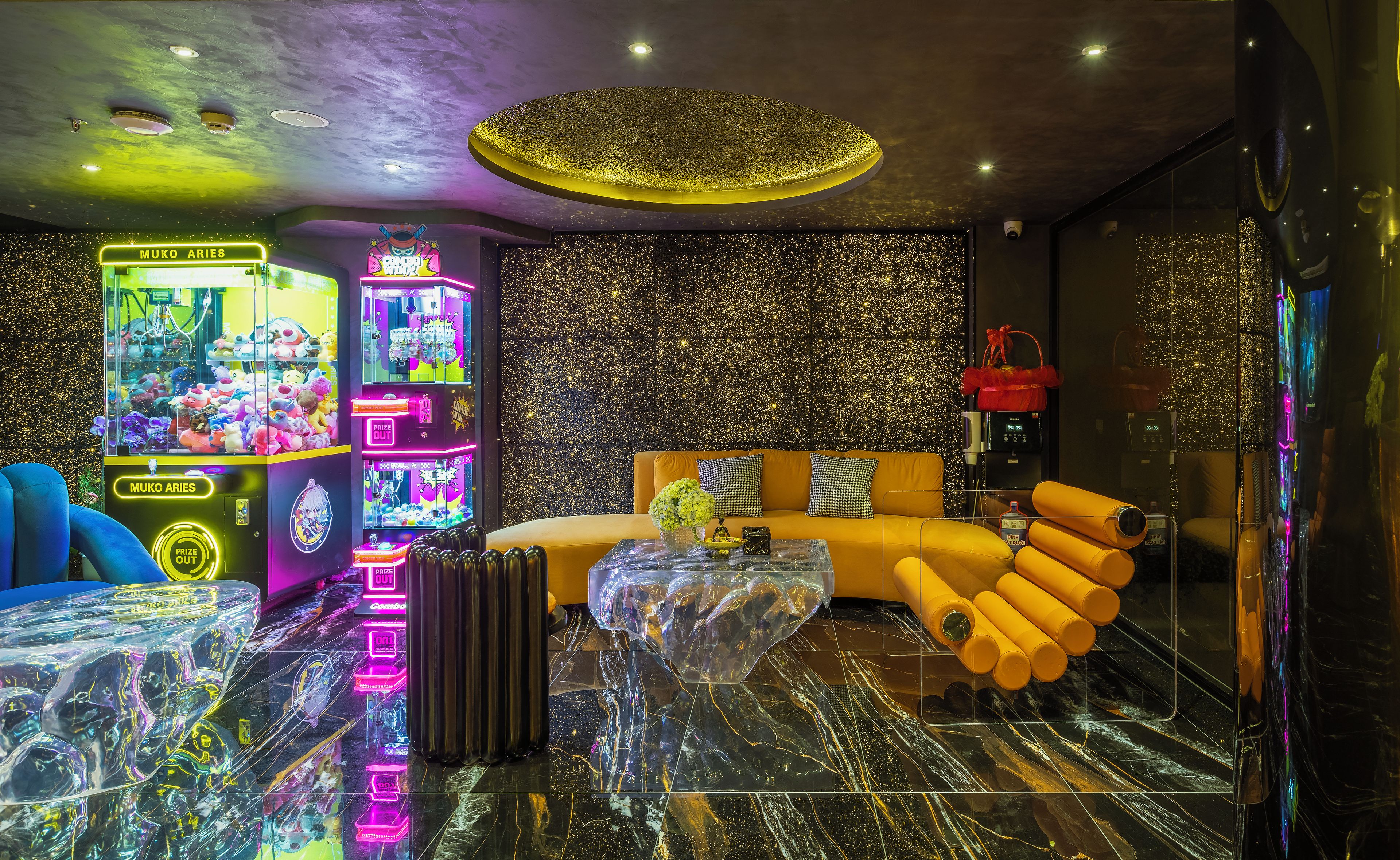 A modern interior with a sofa, a glass coffee table, and claw machines.