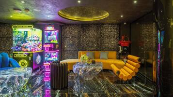 A modern interior with a sofa, a glass coffee table, and claw machines.