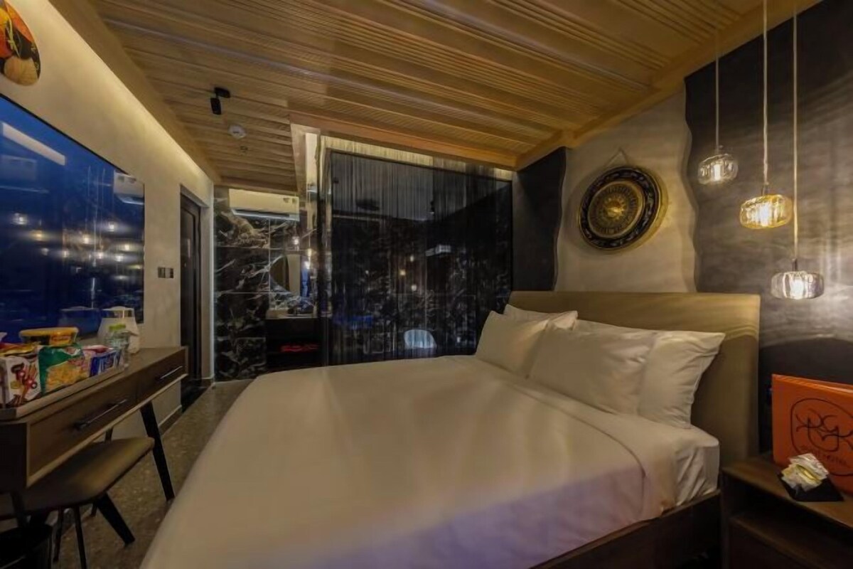 A modern hotel room with a large bed, wooden ceiling, and a city view through the window.